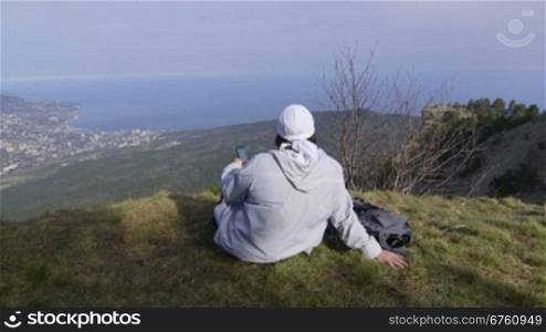 Female hiker with smartphone at mountain top Ai-Petri Crimea, vertical dolly shot