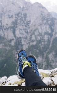 Female hikers shoes at the edge of a cliff. High above the mountains below