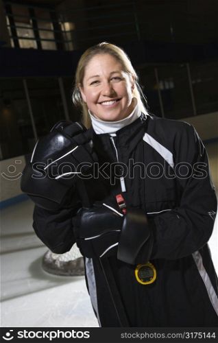 Female hockey coach in uniform standing smiling.