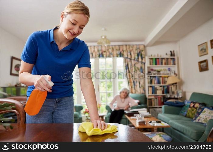 Female Home Help Cleaning House And Talking To Senior Woman