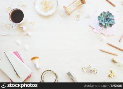 Female home office desk table in golden tones. Workspace with notebooks, cup of coffe, succulent and decorations on light wooden background with copy-space. Flat lay, top view