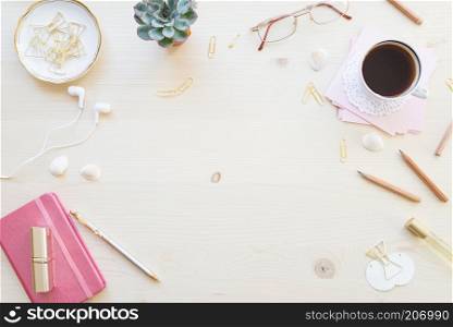 Female home office desk table in pastel tones. Workspace with notebooks, cup of coffe and decorations on light wooden background with copy-space. Flat lay, top view