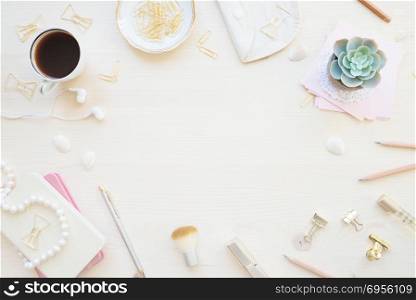 Female home office desk table in pastel tones. Workspace with notebooks, cup of coffe and decorations on light wooden background with copy-space. Flat lay, top view. Female working space in pastel tones