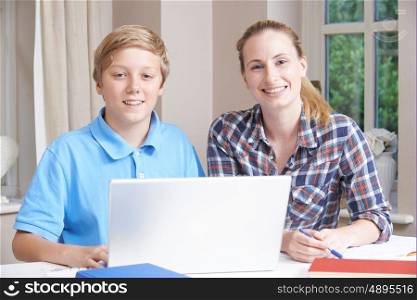 Female Home Tutor Helping Boy With Studies Using Laptop