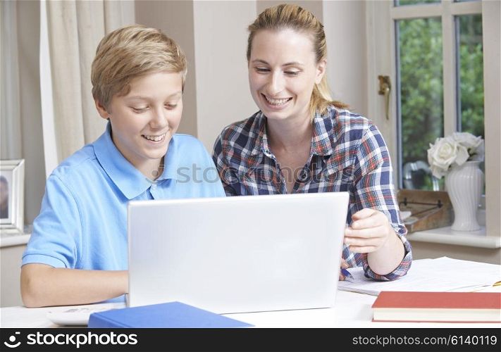 Female Home Tutor Helping Boy With Studies Using Laptop Computer