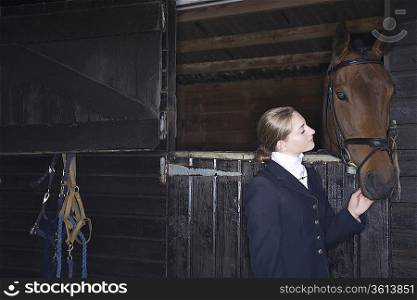 Female horseback rider with horse in stable