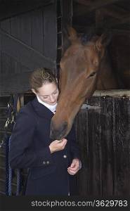 Female horseback rider with horse in stable