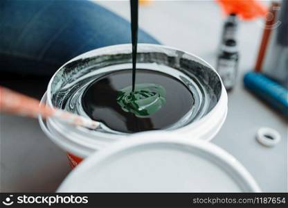 Female house painter mixes black and green paints in pail, closeup. Home repair, laughing woman doing appartment renovation, room decoration renovating. Female house painter mixes black and green paints