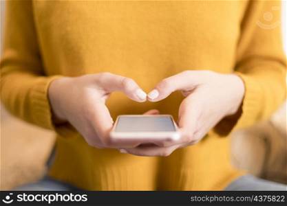 Female in a yellow pullover, using smartphone