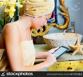 Female in bathroom reading ebook tablet relaxed