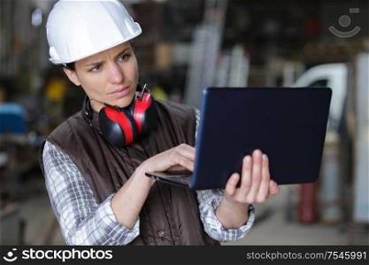 female industrial engineer in the hard hat uses laptop computer