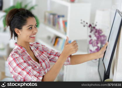 female installing frame on wall at home