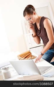 Female interior designer with laptop and phone working at office