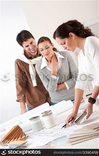 Female interior designer with two clients at office choosing colors