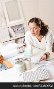 Female interior designer working at office with color swatch and paint