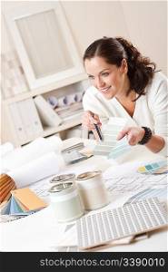 Female interior designer working at office with color swatch and paint