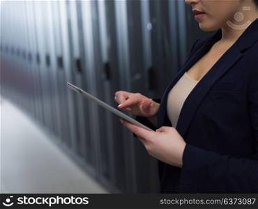 Female IT engineer working on a tablet computer in server room at modern data center