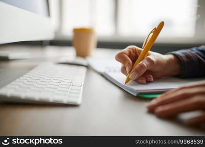 Female IT specialist writes in notepad in office. Web programmer or designer at workplace, creative occupation. Modern information technology, corporate team. Female IT specialist writes in notepad in office