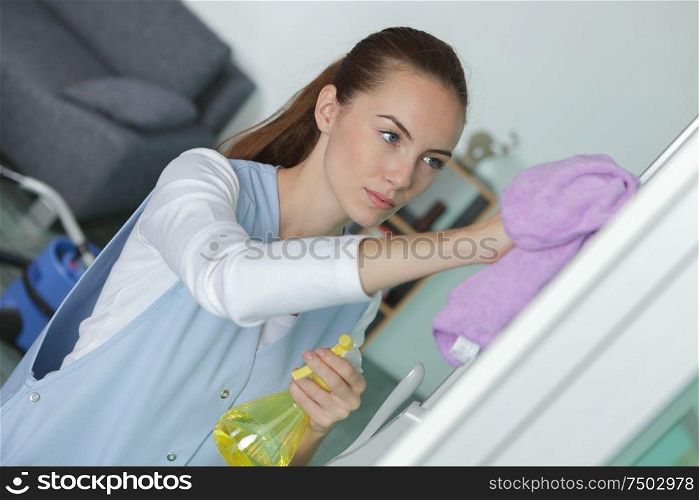 female janitor cleaning refrigerator door with rag