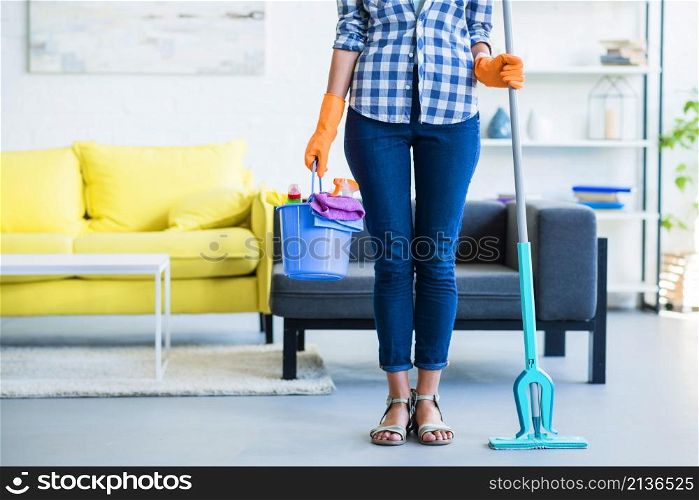 female janitor holding cleaning equipments home