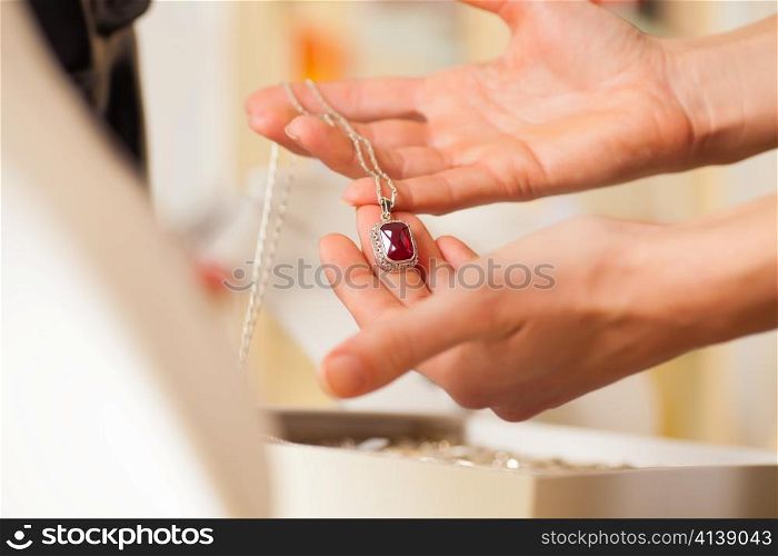 Female jeweller or designer presenting jewellery in her store