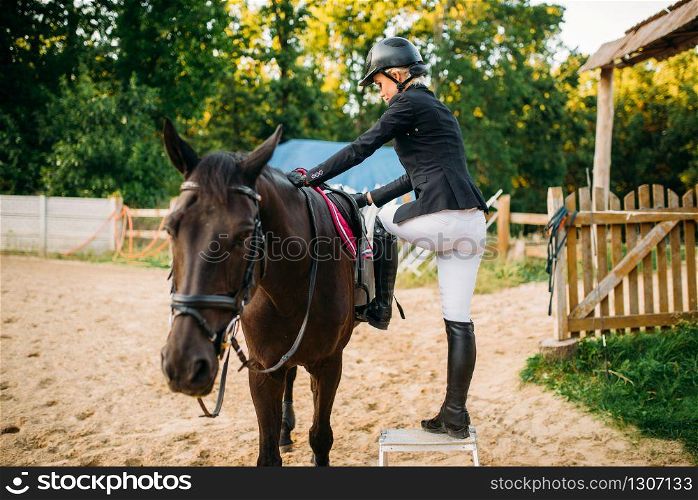 Female jockey and brown stallion, horseback riding. Equestrian sport, young woman and beautiful horse
