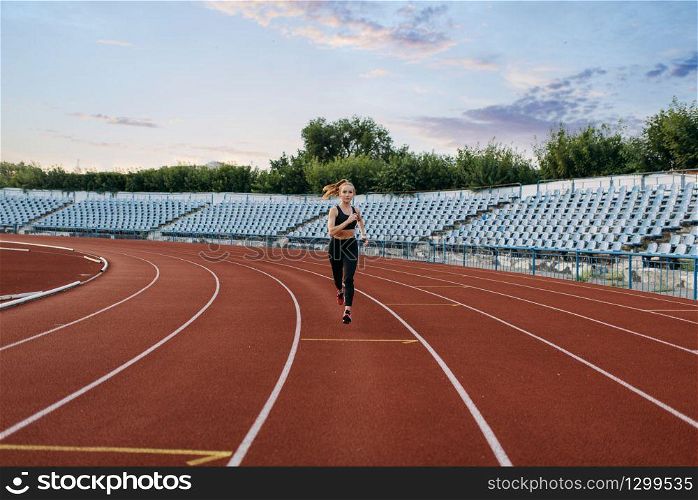 Female jogger in sportswear running, training on stadium. Woman doing stretching exercise before jogging on outdoor arena. Female jogger running, training on stadium