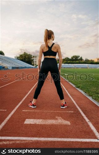 Female jogger in sportswear, training on stadium. Woman doing stretching exercise before running on outdoor arena. Female jogger in sportswear, training on stadium