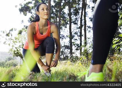 Female jogger tying shoelace in forest