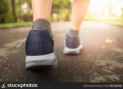 Female jogging in Central Park by wearing sports shoes exercise in the evening sunset.