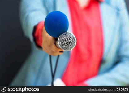 Female journalist at a news conference holding microphone