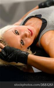 Female kick-boxer laying down on black plexiglass fitness studio