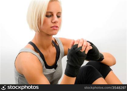 Female kickboxer wrapping wrist into protective bandages on white background