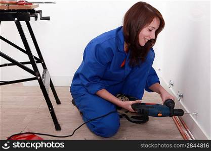 Female labourer drilling hole in wall