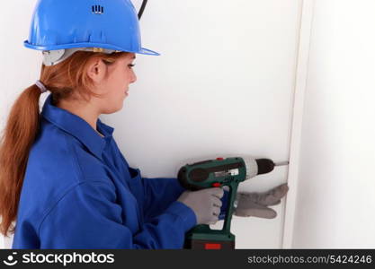 Female labourer drilling hole in wall