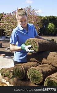 Female Landscape Gardener Laying Turf For New Lawn