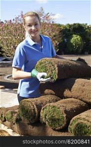 Female Landscape Gardener Laying Turf For New Lawn