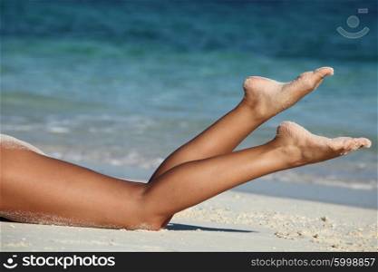 Female legs on beach. Beautiful tan female legs on sea beach