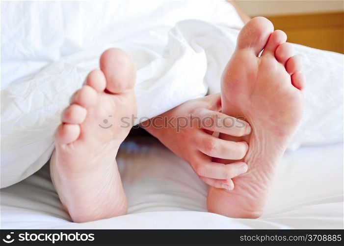 female legs sticking out from under the covers and cards hand