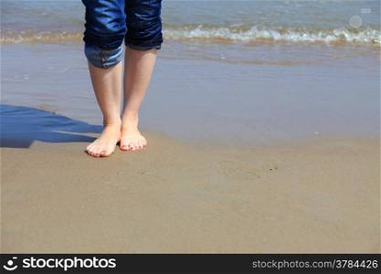 Female legs walking in water, girl&#39;s barefoot legs on the sand beach
