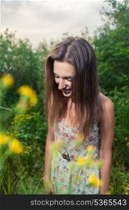 Female looking down and smiling. Beautiful Young Woman standing in Meadow of Flowers.