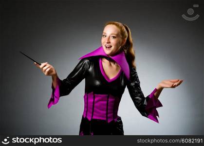 Female magician doing tricks on grey background