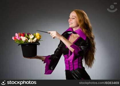 Female magician doing tricks on grey background