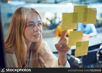 Female manager looks on reminder sheets, IT office. Professional worker, planning or brainstorming. Successful businesswoman works in modern company. Female manager looks on reminder sheets, IT office
