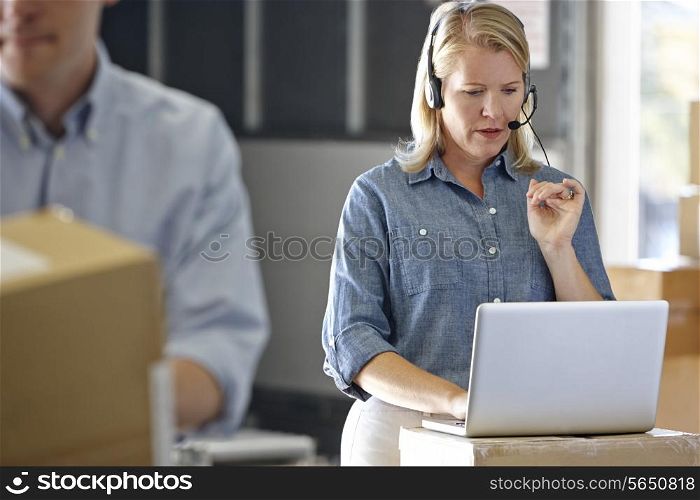 Female Manager Using Headset In Distribution Warehouse