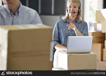 Female Manager Using Headset In Distribution Warehouse