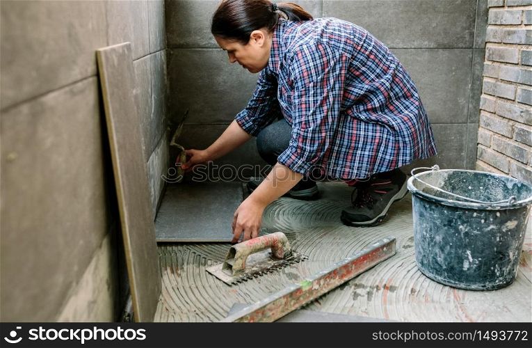 Female manual worker laying a new tile floor on a terrace. Female manual worker laying a new tile floor
