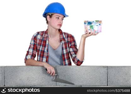 female mason holding a bunch of bills and looking very disappointed