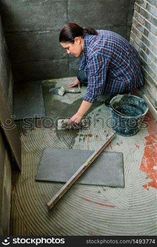 Female mason laying a new tile floor on a terrace. Female mason laying tiles on a terrace