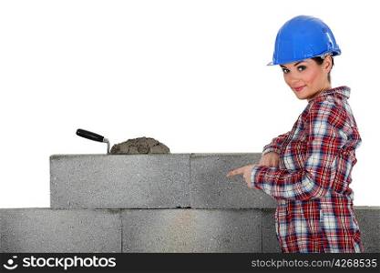female mason pointing at a wall